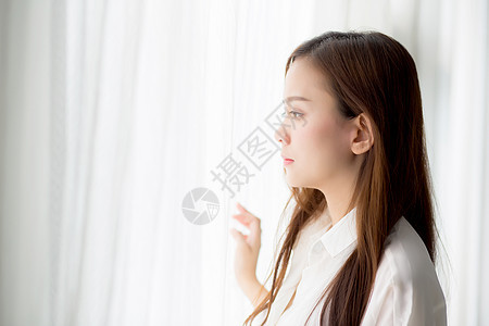 美丽的年轻亚洲女人的肖像 站在窗前房子女性女孩快乐公寓成人房间阳光窗帘幸福图片