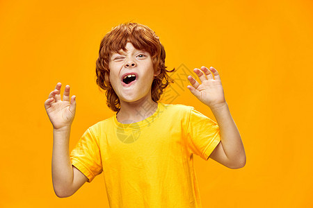 Nimble 红头发男孩举手向前和黄色T恤衫复制空间图片