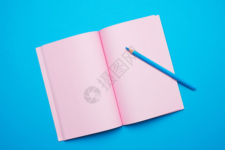 以蓝色背景上的空粉红色工作表打开笔记板图片