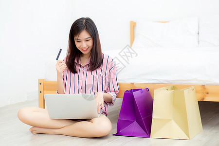美丽的亚洲女人 用笔记本电脑Si在网上购物商业女孩电子商务成人享受卡片女士技术顾客信用图片