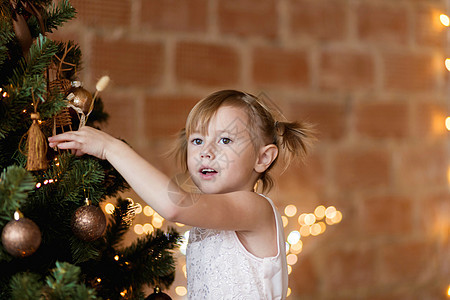 穿着西洋装的可爱小女孩 把圣诞玩具挂在树上礼物盒工作室魔法裙子庆典花环女性礼物假期女士图片