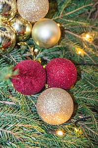 天然杉枝背景上可爱的圣诞闪闪发光的红色和金色玻璃球 带有杉枝和装饰的正宗圣诞背景 垂直框架图片