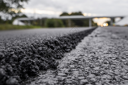 一大层新鲜的热沥青 浅景深中的沥青原料层 滚子在新的道路上滚动新鲜的热沥青 道路建设 修建一条新路材料柏油石头路面粒状铺路路线机图片