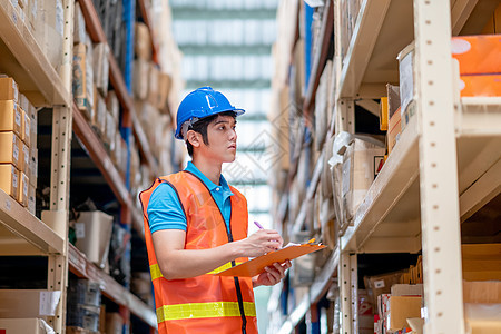 仓库工人或工厂工人 头戴蓝色安全帽 在货架和支票包之间站着制服图片