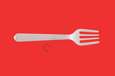红色背景上的一个塑料白叉子 隔离 顶端视图图片