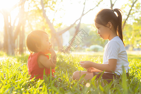 美丽的年青年轻小孩 夏天在公园玩耍的时候坐在公园里朋友们乐趣幸福姐姐假期活动闲暇女士孩子们快乐图片