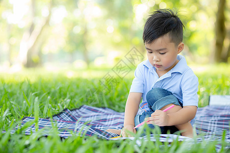 在公园里读和写书的年轻小男孩 Asi孩子们微笑绘画学习学校阅读童年男性儿子课堂图片