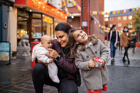 在唐人街的小巷里 妇女与两个女儿一同跪在一旁幸福孩子们家庭肺炎口罩母亲女士街道女性旅行图片