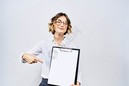 浅色背景和发型眼镜模特手里拿着一个白色文件文件夹的女商务人士黑发手指性格成人工作人士广告商务工作室商业图片
