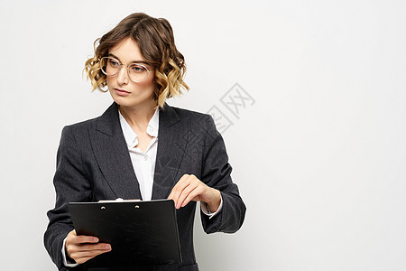 身着西装 证件在轻背景下持有文件的女商务人士 卷卷卷头发发型工人套装快乐成人成功管理人员女孩女士工作商务图片