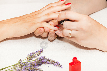将指甲油涂在女人的手上卫生指甲粉色手指沙龙治疗白色抛光美甲师温泉图片