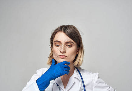 穿着蓝色医疗手套的情感女性触碰头部 手放在浅薄的背景上白色外套护士外科药品微笑专家职业诊所女士图片