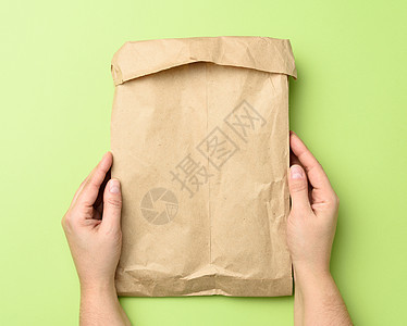 两只手拿着纸袋 包着棕色的Kraft纸杂货店牛皮纸解雇午餐环境折叠生态店铺商业羊皮纸图片