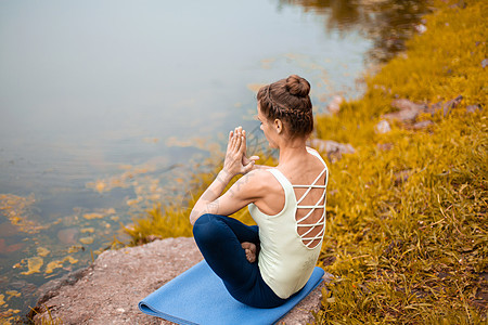 一名年轻运动女运动员在河边的黄草坪上做瑜伽 使用瑜伽类动物的姿势沉思训练体操活力生活方式身体平衡瑜珈海滩灵活性图片