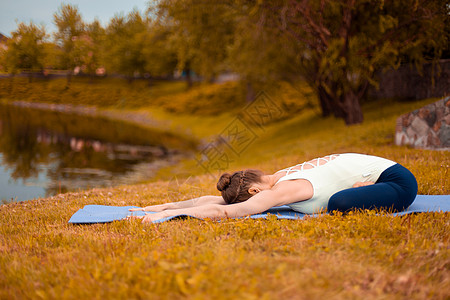 浅黑发女孩去参加运动 在湖底坠落的自然中做瑜伽姿势图片
