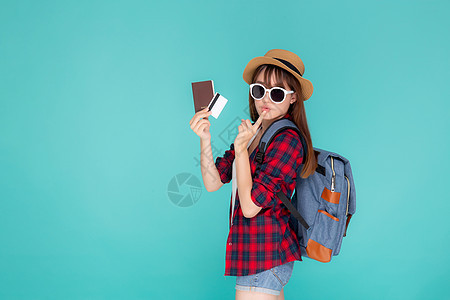 美丽的年青年轻女士戴着帽子和墨镜展出航程乐趣闲暇护照眼镜女性游客旅游支付蓝色图片