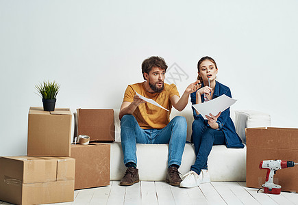 一男一女坐在箱子旁边沙发上的沙发上 有些东西在房间内部移动互联网公寓地面微笑纸板女士抵押搬迁夫妻盒子图片