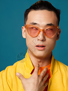 一个英俊的亚洲男人 戴眼镜 用手做黄色夹克手势图片