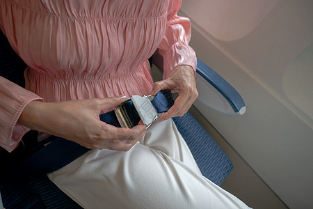 近身的女子系好飞机安全带女士座位带子腰带空气安全女孩危险警告航班图片
