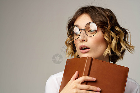手持笔记的女商务人士 工作米色背景眼镜发型办公室经理微笑成功管理人员黑发女士女孩成人工作室图片