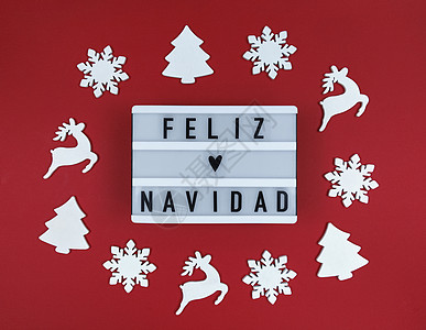 光盒与短语 西班牙圣诞快乐 在红色背景和木制玩具图片