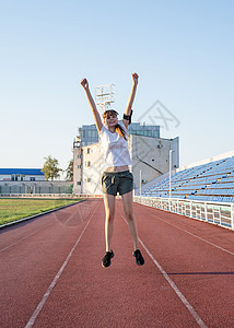 快乐的体育女运动员在体育场跳跃图片