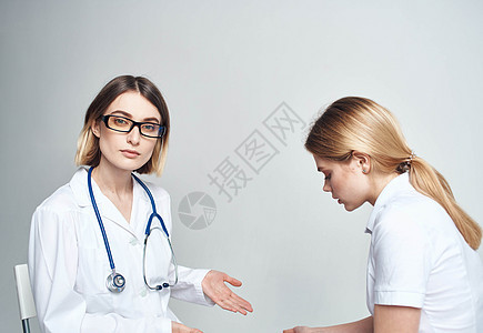 医生坐在椅子上 女病人在室内用浅薄背景作物景色观看护士访问医院男人心脏病卫生快乐药品专家医师图片