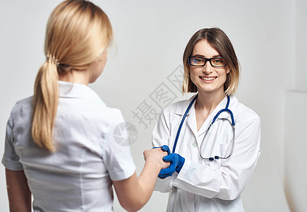 护士用轻光背景和蓝色手套与病人握手 并配有听诊器卫生男人保健咨询服务诊所女性诊断药品专家图片