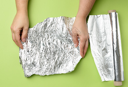两只雌性手握着一个绿色的背角上 折叠的银子磨砂身体包装灰色皱纹光泽度垃圾女士锡纸反射图片