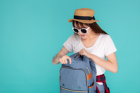 美丽的肖像 年轻的亚洲女性 戴着太阳眼镜和帽子工作室潮人女士旅游背包假期航程成人蓝色快乐图片