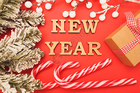 庆祝新年快乐 红色背景中新年帽中的木字 上面有绿色云杉枝 糖果 礼盒和雪 节日装饰或明信片概念风格礼物盒子季节数字假期海报快乐云图片