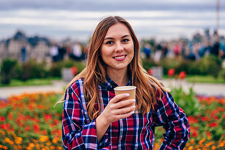 美丽的年轻女士拿着咖啡杯和微笑着笑容杯子咖啡女孩金发女郎食物女性日落公园快乐头发图片