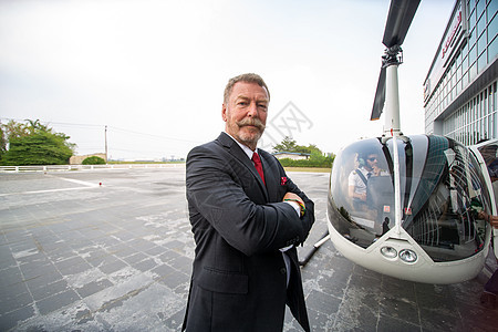 乘坐直升机旅行的商务人士 一名成熟商务人士在乘坐直升机旅行时使用耳机的照片航班男人车辆奢华飞行员管理人员飞机场私人职业商业图片