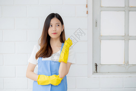 画像中的年轻亚洲女性是戴着橡胶手套和围裙的管家 用于在家保护 女佣制服 清洁和洗涤 女孩站立工人积极 一个人 生活方式概念主妇工图片