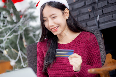 年轻的亚洲女性在圣诞节用笔记本电脑上的信用卡在线购物 女性用借记卡购买和支付 圣诞节在假期 新年快乐 顾客在网上购物卡片金融销售图片
