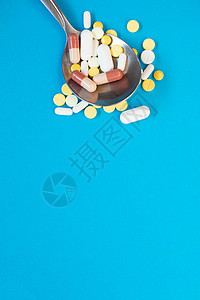 将药丸倒入不锈钢勺子 圆形和椭圆形药片中 各种颜色用于治疗各种疾病 蓝色背景技术剂量药物处方药剂制药药店药品疼痛科学图片