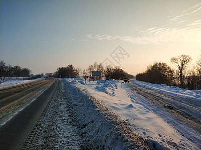 冬季风景 一条白雪覆盖的公路 汽车沿路行驶场景暴风雪痕迹农村天气日落太阳沥青运输天空图片