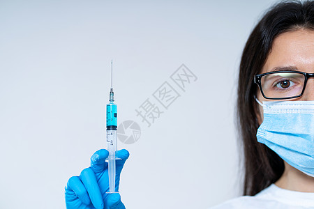 戴着医用口罩和手套的年轻女医生拿着一个注射器 里面装有冠状病毒疫苗和疫苗芯片 阴谋论 砍人创新科学治愈药品实验室眼镜流感控制面具图片