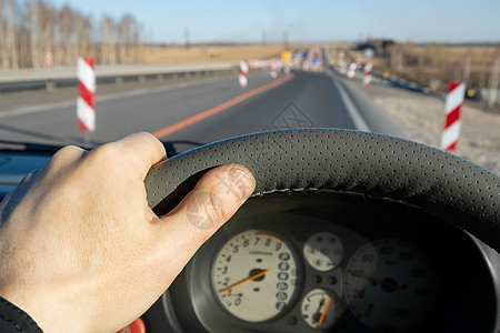 正在修护围栏的道路背景下 司机把手放在汽车的方向盘上图片