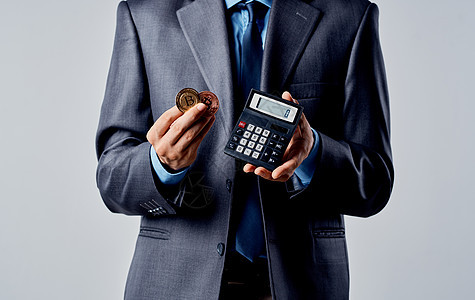 手握计算器和加密货币比特币Bitcoin财富汇率的商务人士交换商业密码金子投资贸易套装网络现金男人图片