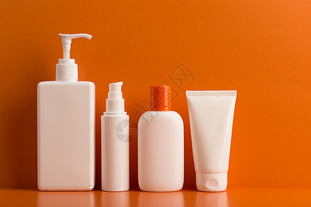 夏季在橙色背景下为皮肤和身体护理提供一套防晒霜化妆品图片