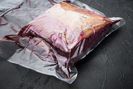 纽约牛肉牛排在塑料袋中切割 黑背景图片