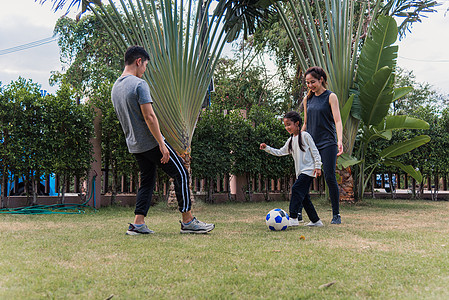 母亲 父亲和子女的女儿在自然外踢足球 野外一个园林公园童年喜悦游戏微笑闲暇公园足球女性爸爸花园图片
