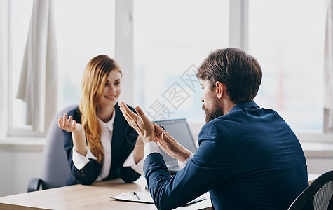 一个穿西装的商务人士和一个女人在办公室的桌子上在工作中相互交流男性合伙男人商业商务人士女士同事互联网电脑图片