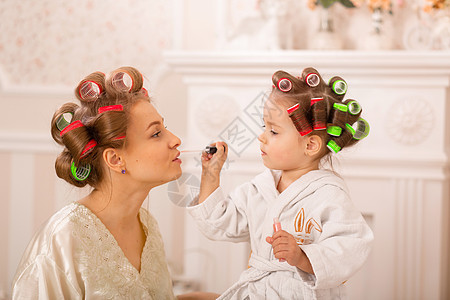 可爱的小女孩和她妈妈在卷发器上化妆 妈妈教女儿使用化妆品 美容日 女孩就是这样的女孩孩子魅力女性浴衣口红母性母亲闲暇童年发型图片