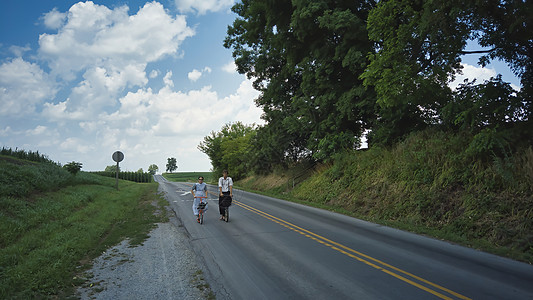 两名阿米什青少年 一名男孩和一名女孩乘坐滑脚车历史农业车辆旅行运输马车农民牧场传统历史性图片