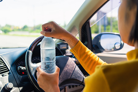 妇女驾驶汽车时用水瓶饮酒 女交通女孩男性司机青少年运输女士瓶子成人车轮图片