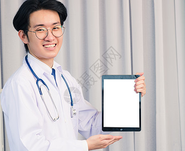 身穿制服和听诊器颈部带的医生 手持智能数字平板电脑显示前空屏幕保健男性职业卫生药品实习生医院专家技术从业者图片