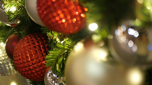 在模糊的闪闪发光的仙女背景上 用明亮的红球装饰的户外圣诞树的特写镜头 散焦花环灯散景效果 圣诞快乐和节日快乐的概念花环假期金子风图片