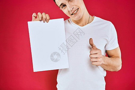 持有纸质复制空间T恤红色背景材料的情绪型男子推介会广告人士成功标语衬衫卡片男人微笑工作室图片